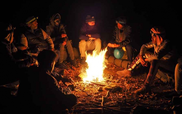 a group of students sit around a campfire on an outward bound course in the blue ridge mountains